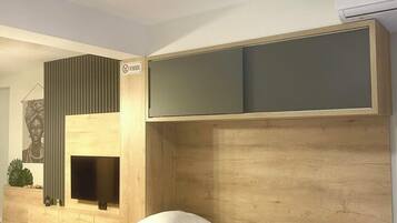 Ein modernes Schlafzimmer mit einem hölzernen Kopfteil, einem Flachbildfernseher, einem kleinen Kamin und einem Bett mit weißer Bettwäsche.