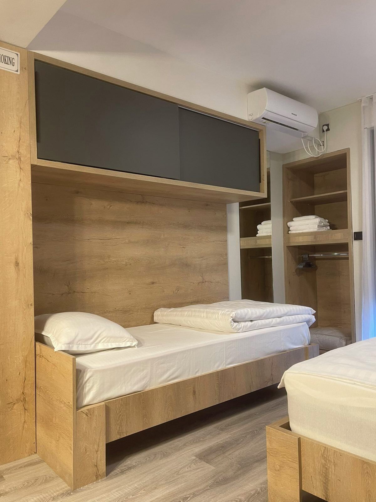 A bunk bed with a built-in TV and storage shelves, a shower area, and a wooden floor.