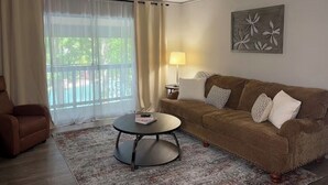 Uma sala de estar com um sofá marrom, uma mesa de centro redonda, um abajur e um quadro na parede.