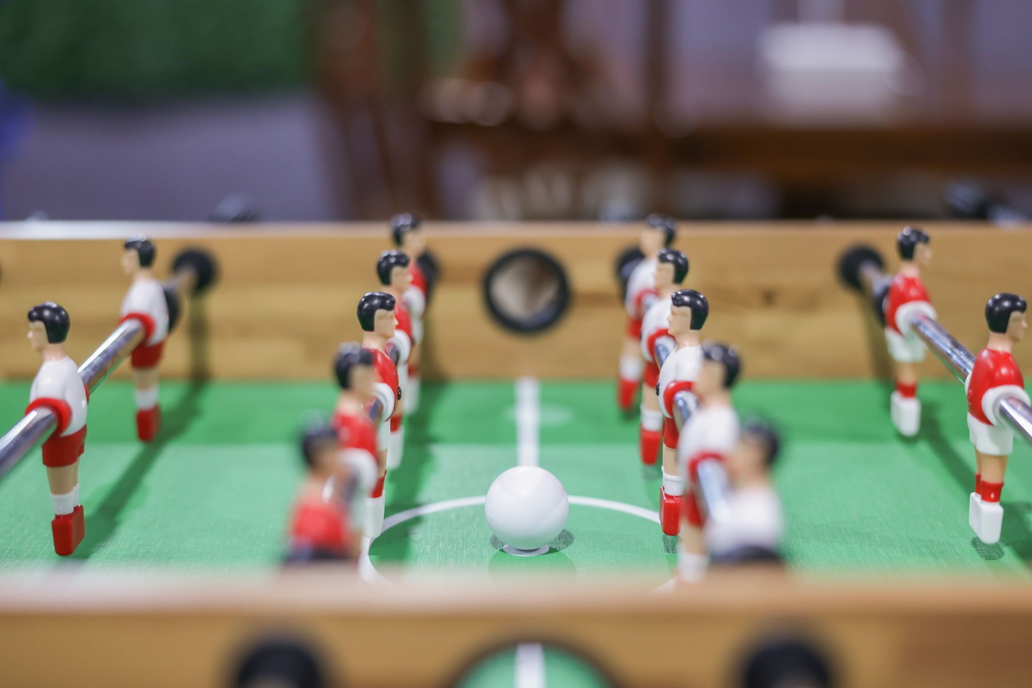 Een close-up van een tafelvoetbaltafel met spelers in rode en witte tenues.