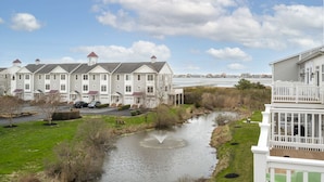 A waterfront property with a river, a large white building with multiple chimneys, and a smaller white building with a balcony. - Seaside Village 4 by Seaside Vacations & Sales (Ocean City)