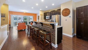 A kitchen with a brick backsplash, stainless steel appliances, and a large wall clock. - Seaside Village 4 by Seaside Vacations & Sales (Ocean City)