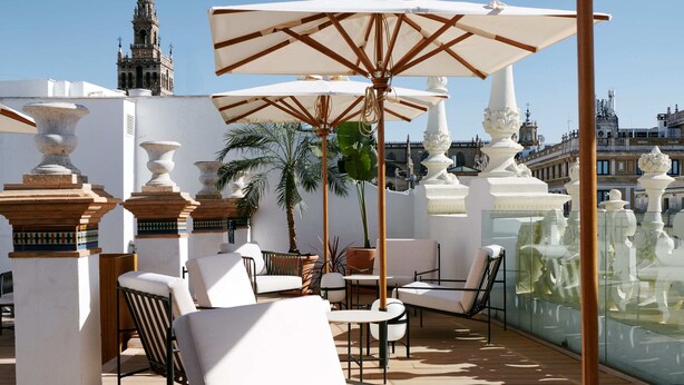 A rooftop terrace with outdoor seating, umbrellas, and a view of historic buildings. - Mercer Plaza Sevilla 5 GL (Seville)