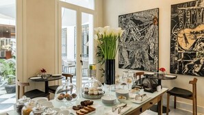A breakfast buffet setup with jars of spreads, a vase of flowers, and a large black and white artwork on the wall. - Mercer Plaza Sevilla 5 GL (Seville)