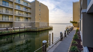 A waterfront hotel with a wooden dock leading to a pier, surrounded by calm water. - Wight Bay 559 by Seaside Vacations & Sales (Ocean City)