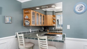 A kitchen with a bar area, wooden cabinets, and a clock on the wall. - Wight Bay 559 by Seaside Vacations & Sales (Ocean City)