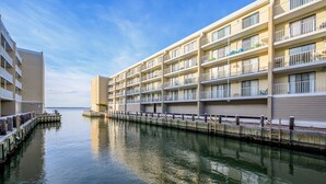 A waterfront hotel with multiple balconies, a dock, and a calm water body. - Wight Bay 559 by Seaside Vacations & Sales (Ocean City)