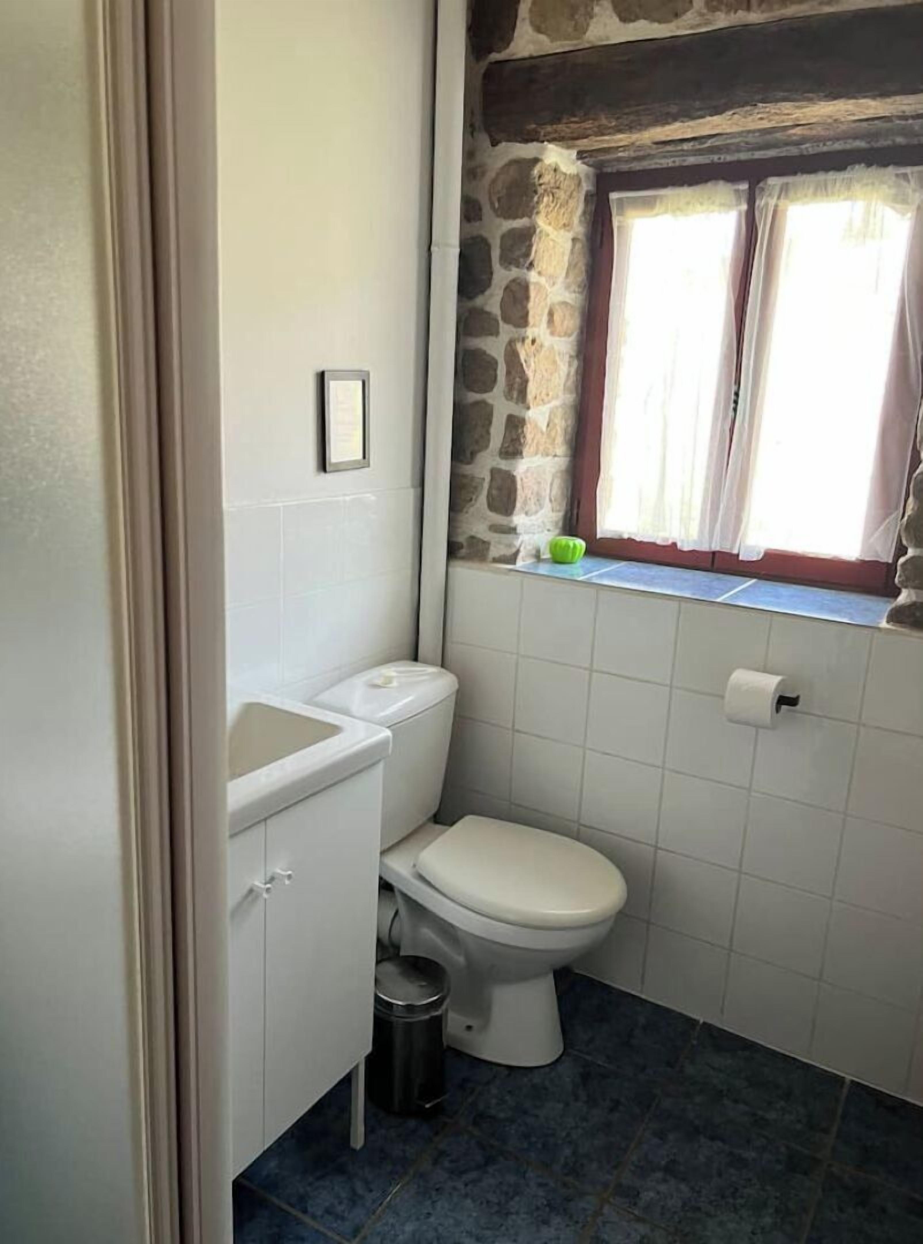 Un baño pequeño con inodoro, lavamanos y ventana con cortinas.
