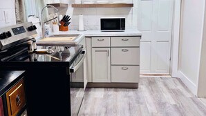 A modern kitchen with a stove, microwave, and cabinets.