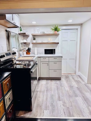 A modern kitchen with a stove, microwave, and cabinets. - Creekside Cabin w Hot Tub, Fire Pit, Deck & Grill! (Mount Jackson)