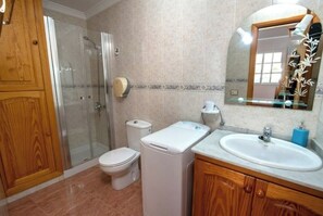 A bathroom with a glass shower enclosure, a toilet, a washing machine, and a sink with a mirror above it. - Apartamento Estudio Mirador de los Poetas (Puerto de las Nieves)