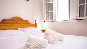 A neatly made bed with white linens and two rolled towels on the bed. - Apartamento Estudio Mirador de los Poetas (Puerto de las Nieves)