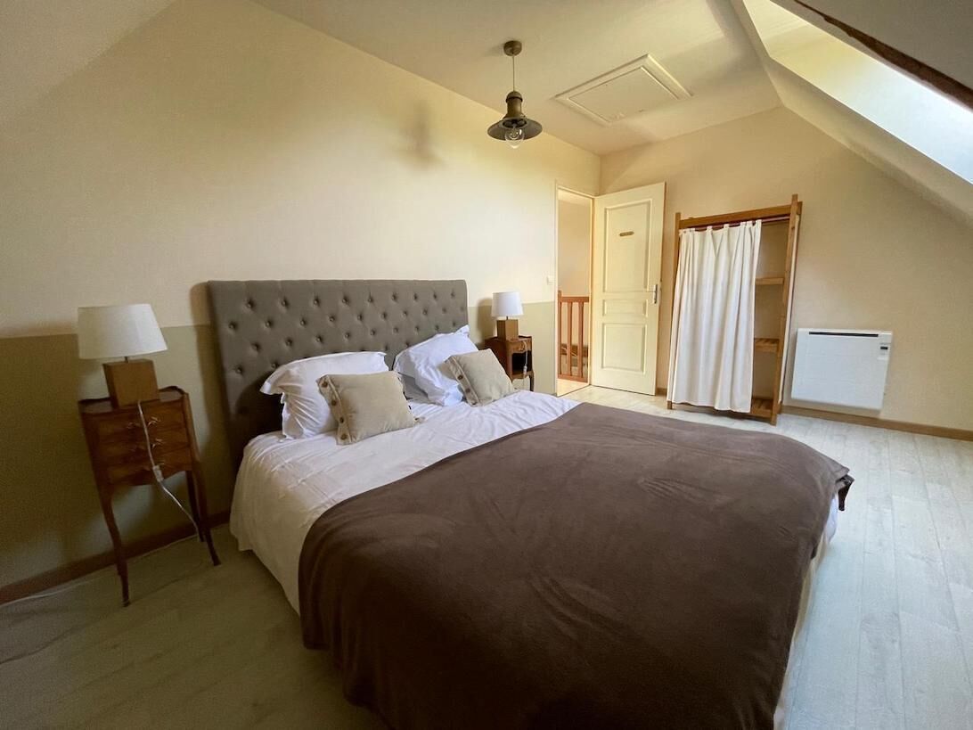 A bedroom with a large bed, two bedside tables with lamps, a ceiling fan, and a door with a curtain.