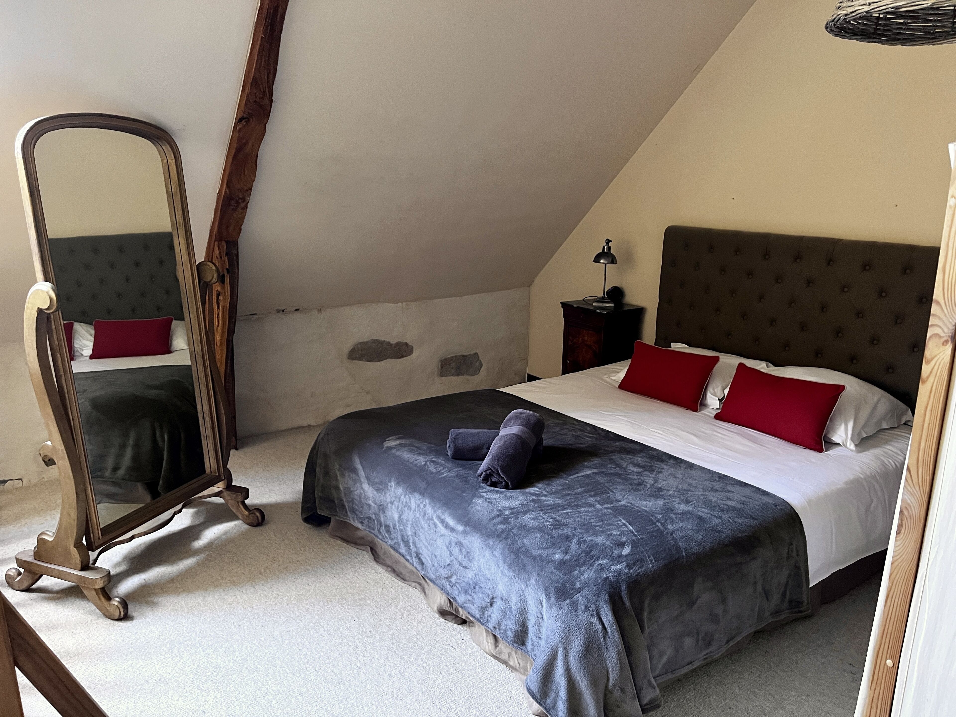 Un dormitorio con una cama grande, un aparador de madera, un espejo y una lámpara.