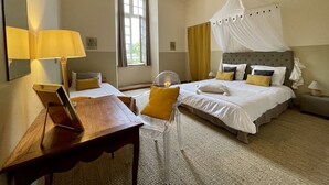 A bedroom with a bed, bedside table, lamp, and a chair.