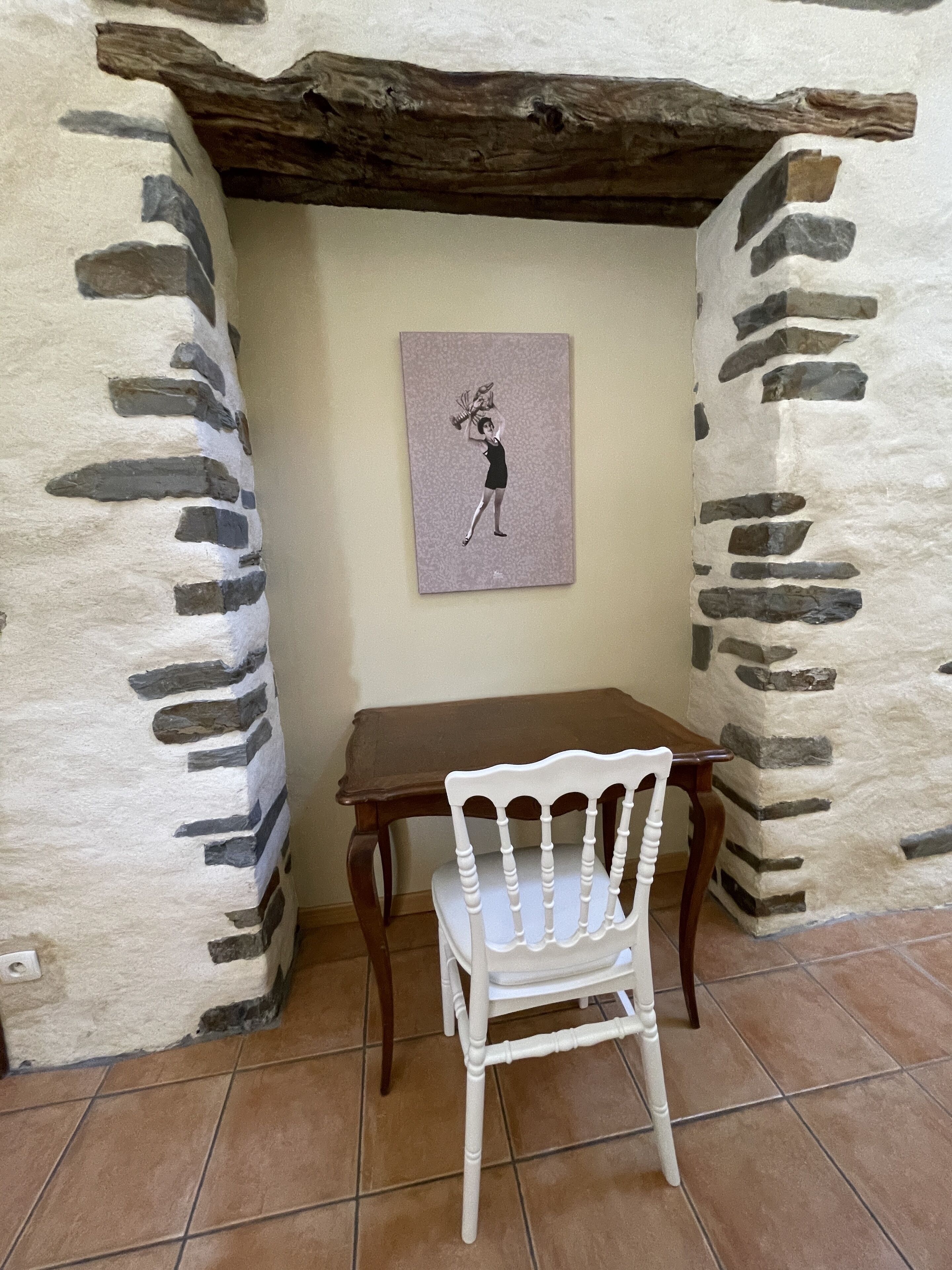 Eine Steinmauer mit einem Holztisch und einem weißen Stuhl davor.