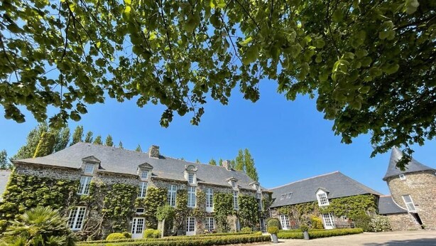 A stone building with a symmetrical facade, large windows, and a well-maintained garden.