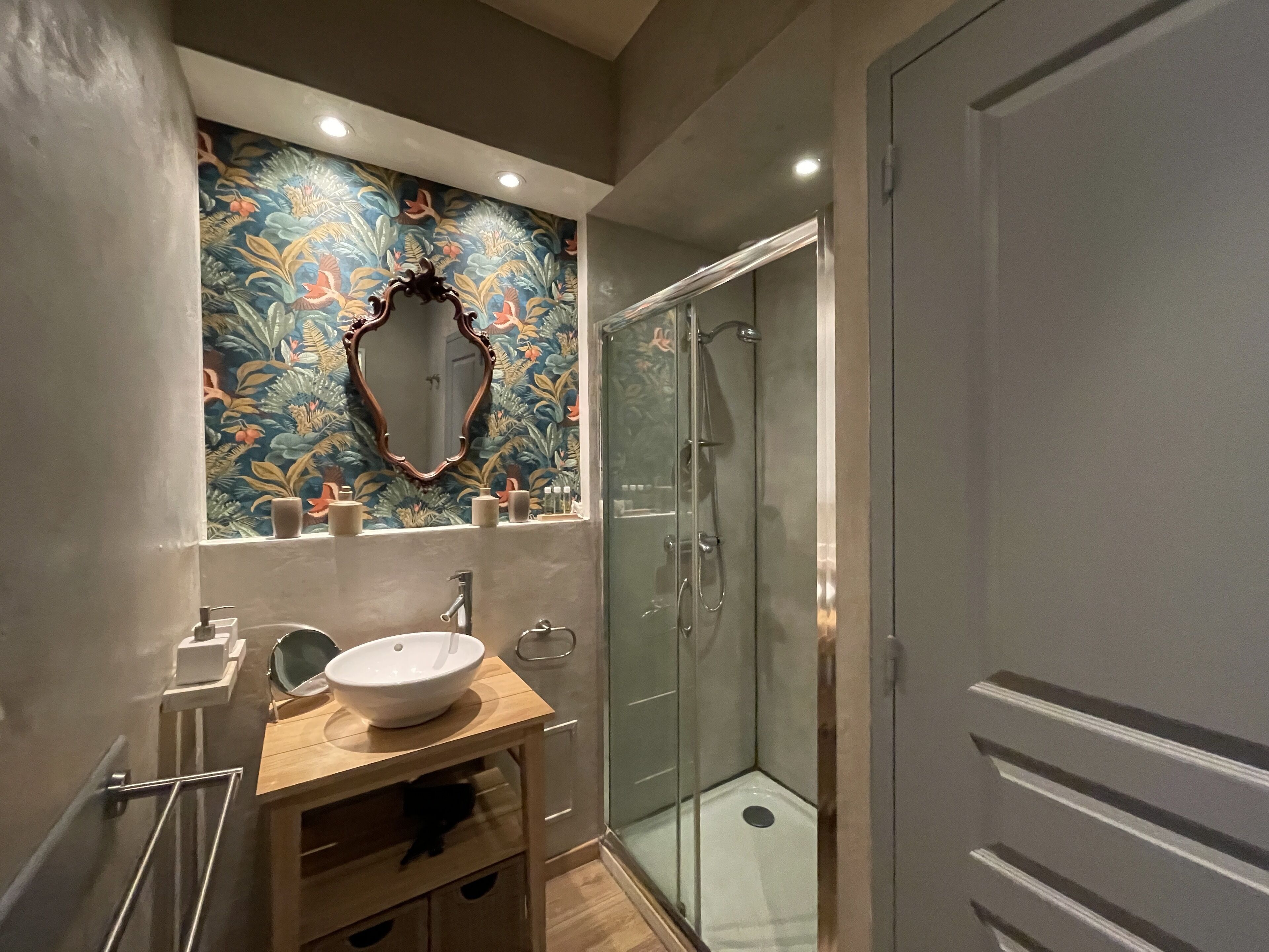 A bathroom with a wooden vanity, a large mirror, a sink, and a glass shower enclosure.