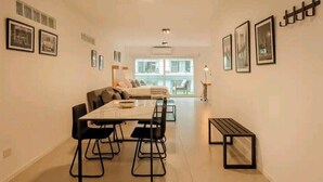 Una sala de estar moderna con comedor, que incluye un sofá, una mesa de centro y una mesa de comedor con sillas.