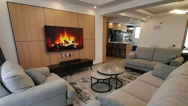 A modern living room with a flat-screen TV, a fireplace, and a sofa set. - Maya 3-bed Apartment in Nairobi (Nairobi)