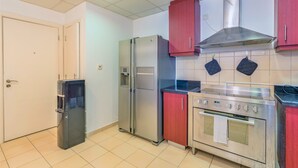 Una cocina con electrodomésticos de acero inoxidable, un armario rojo y piso de baldosas.