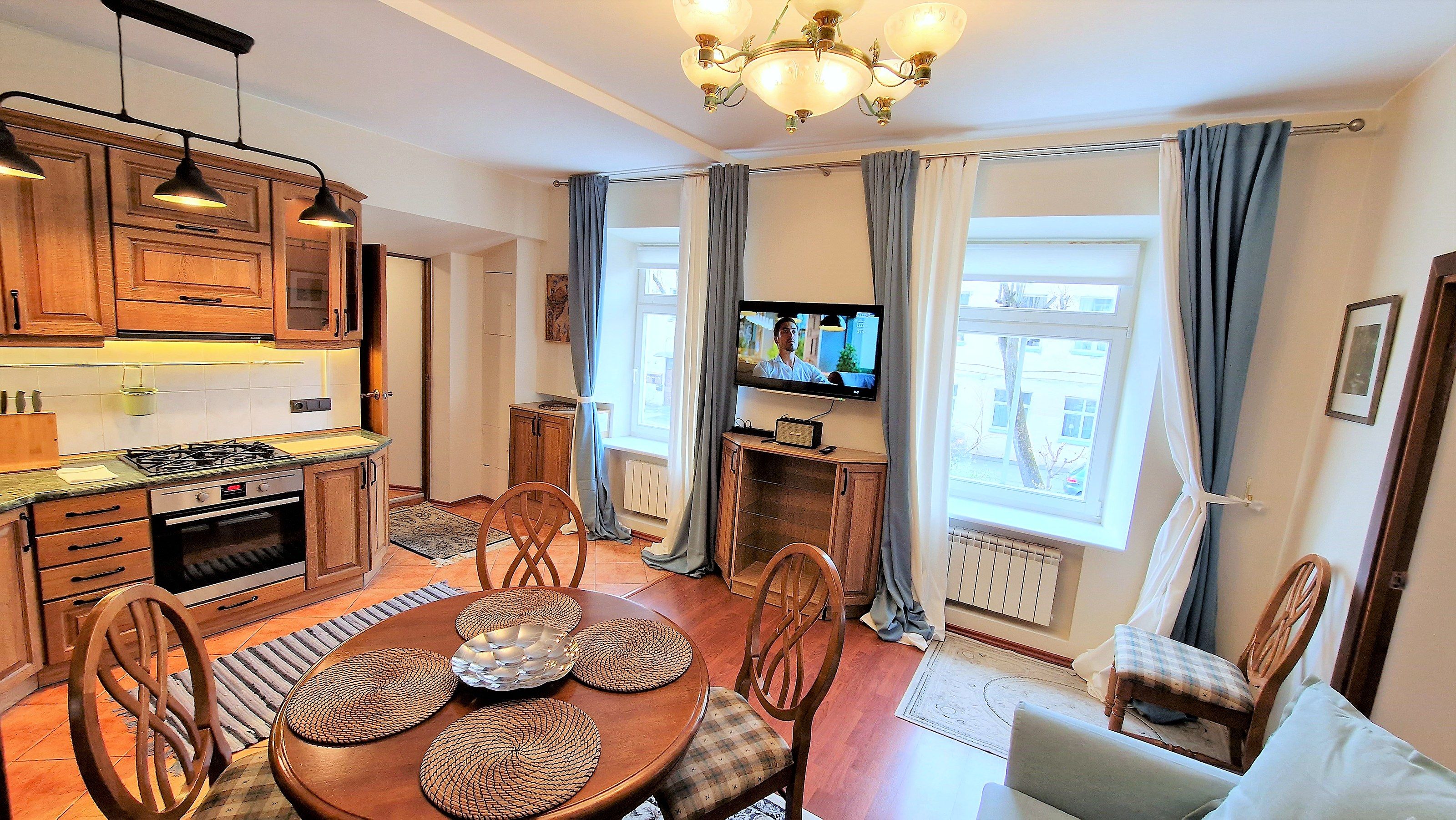 A kitchen with wooden cabinets, a gas stove, and a dining area with a round table and chairs.