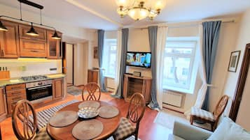 A kitchen with wooden cabinets, a gas stove, and a dining area with a round table and chairs.