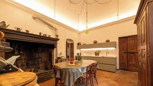 A traditional kitchen with a fireplace, a dining table with chairs, and a modern kitchen area. - Palazzo Rosati 1701 – An 18th-Century Palace with a Stunning View over Lake Como (Bonzanigo)