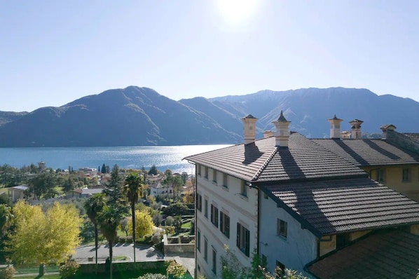 Un edificio con tejado de baldosas, vista a un lago y montañas al fondo.