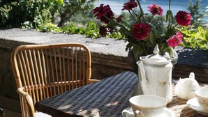 A wicker table with a white teapot, cups, and a vase of flowers. - Palazzo Rosati 1701 – An 18th-Century Palace with a Stunning View over Lake Como (Bonzanigo)