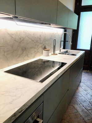 Una cocina con encimera de mármol, estufa integrada y pileta.