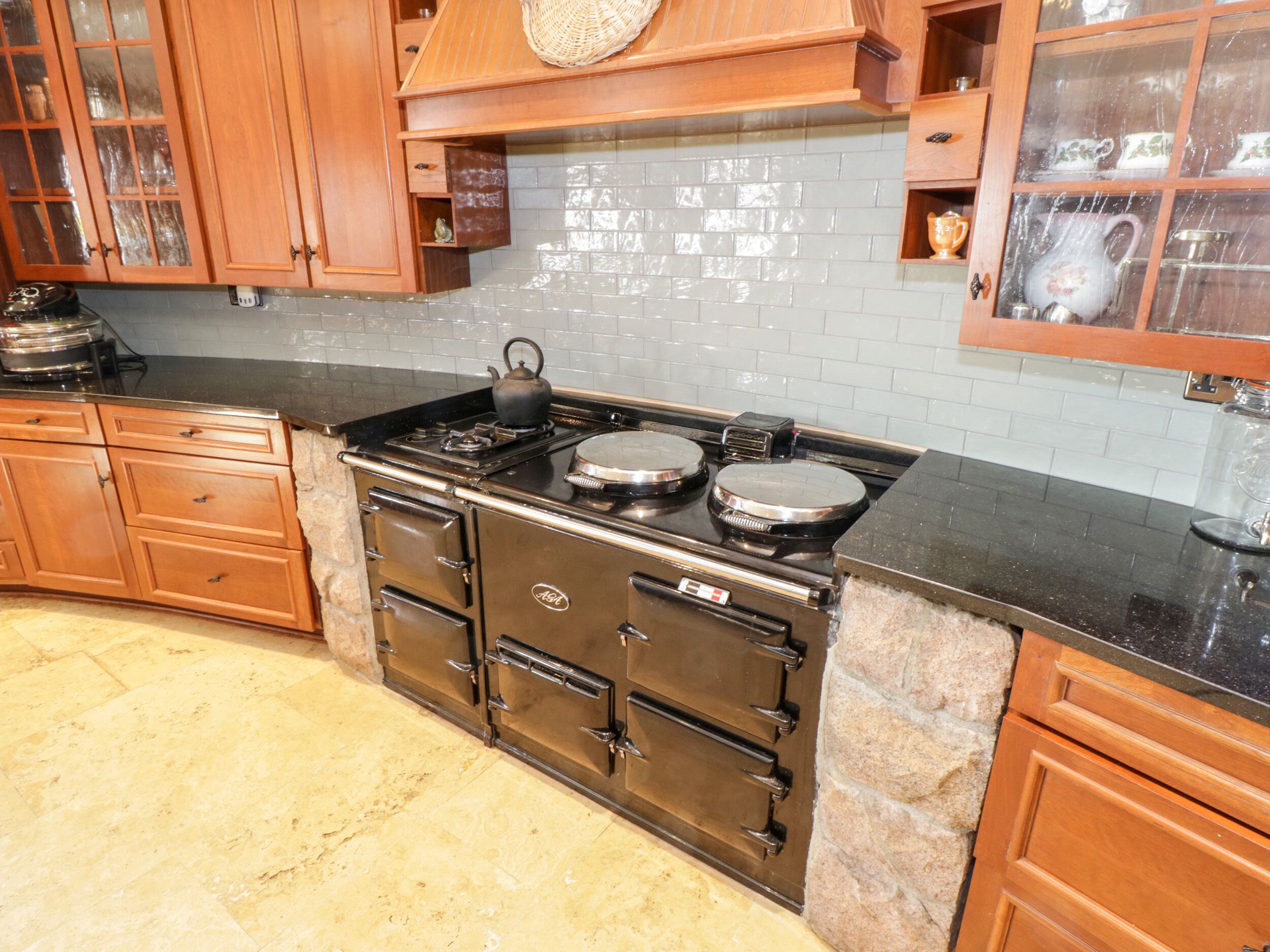 A kitchen with wooden cabinets, a black countertop, and a tiled backsplash.