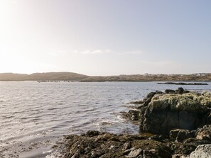 A coastal landscape with rocky shores and calm waters. - Baile Na Cille (Maumeen)