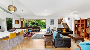 A spacious living area with a dining area, a black leather sofa, a wooden coffee table, and a bookshelf. - Welcome to "Buddha Beach House," the perfect beach retreat in coastal haven Sawtell. (Sawtell)