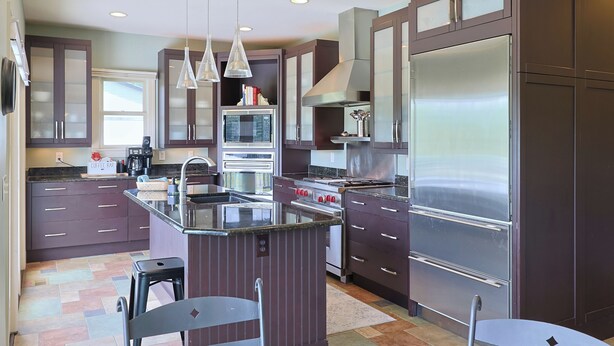 A modern kitchen with dark cabinetry, stainless steel appliances, and pendant lighting. - The Hanger House on Lake Norman Airpark (Mooresville)