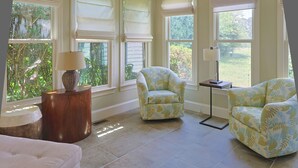 A room with a large window, a chair, a lamp, and a round table. - The Hanger House on Lake Norman Airpark (Mooresville)
