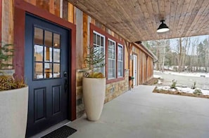 A wooden cabin with a dark door, large windows, and a covered porch.