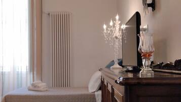 A bedroom with a bed, a dresser, a mirror, a chandelier, and a radiator.