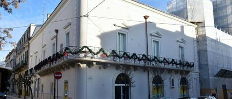 A white building with a balcony, parked cars, and a no entry sign.