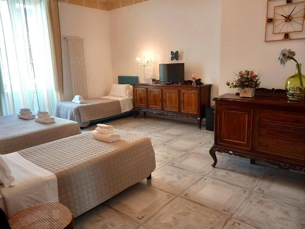 A hotel room with two beds, a wooden dresser, a television, and a clock on the wall.