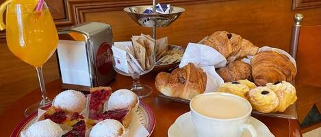 A breakfast table with pastries, a drink, and a coffee cup.
