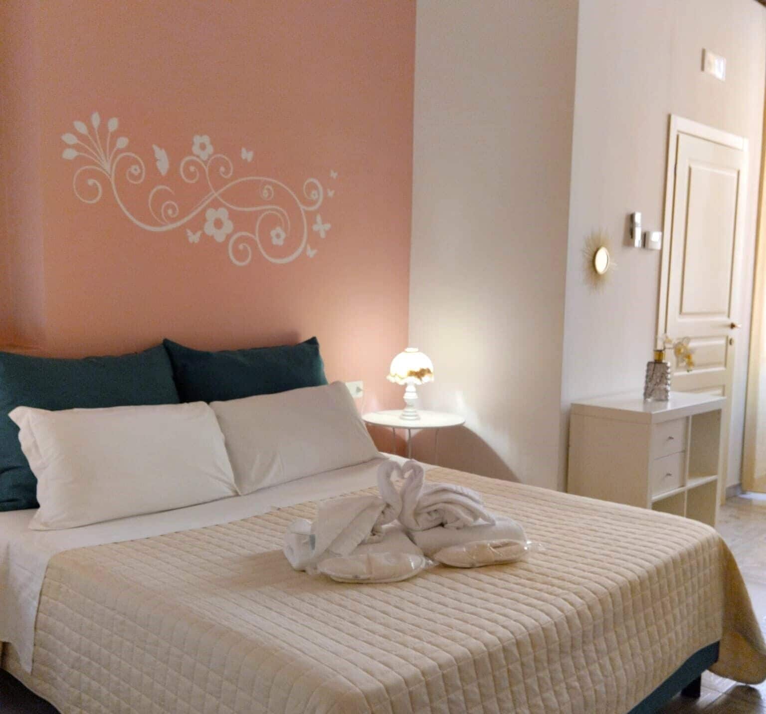 A neatly made bed with a quilted cover, two pillows, and a decorative towel arrangement on the bed.