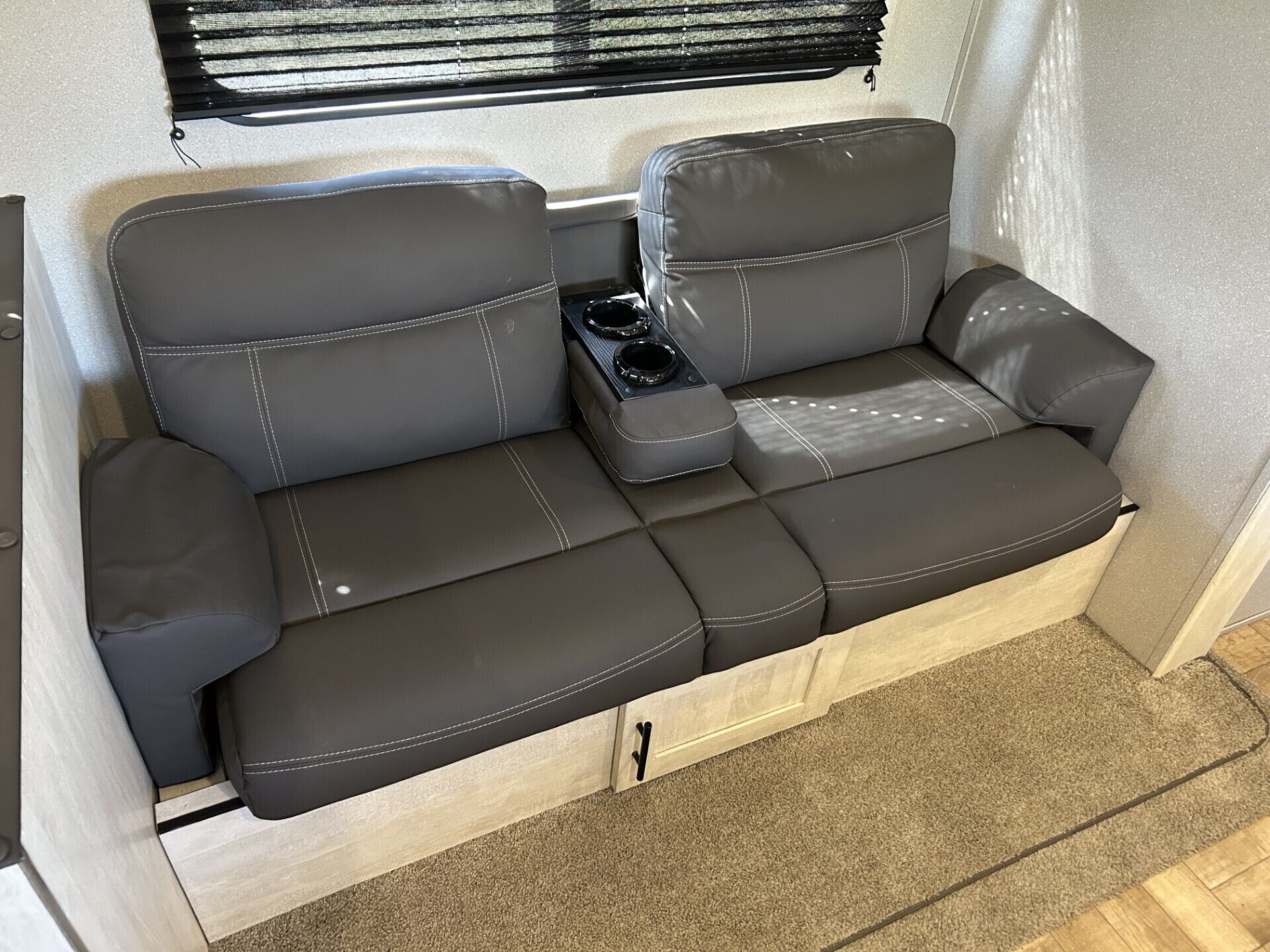 A compact, two-seater sofa with a light wood frame and a small storage compartment.