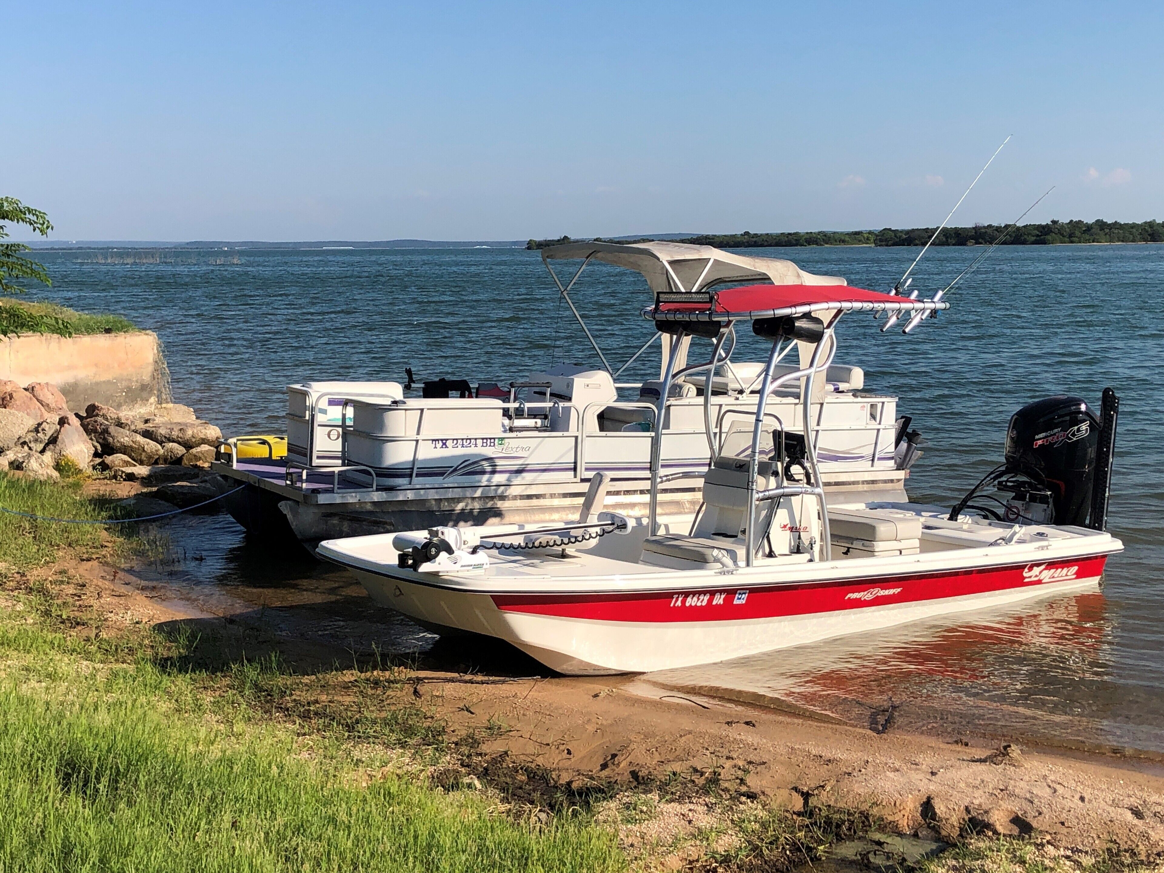 A boat docked at a sandy shore with a clear view of the water and distant land.