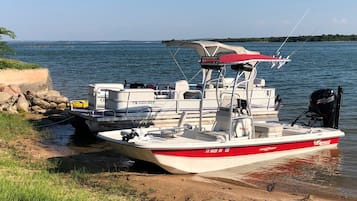 A boat docked at a sandy shore with a clear view of the water and distant land.