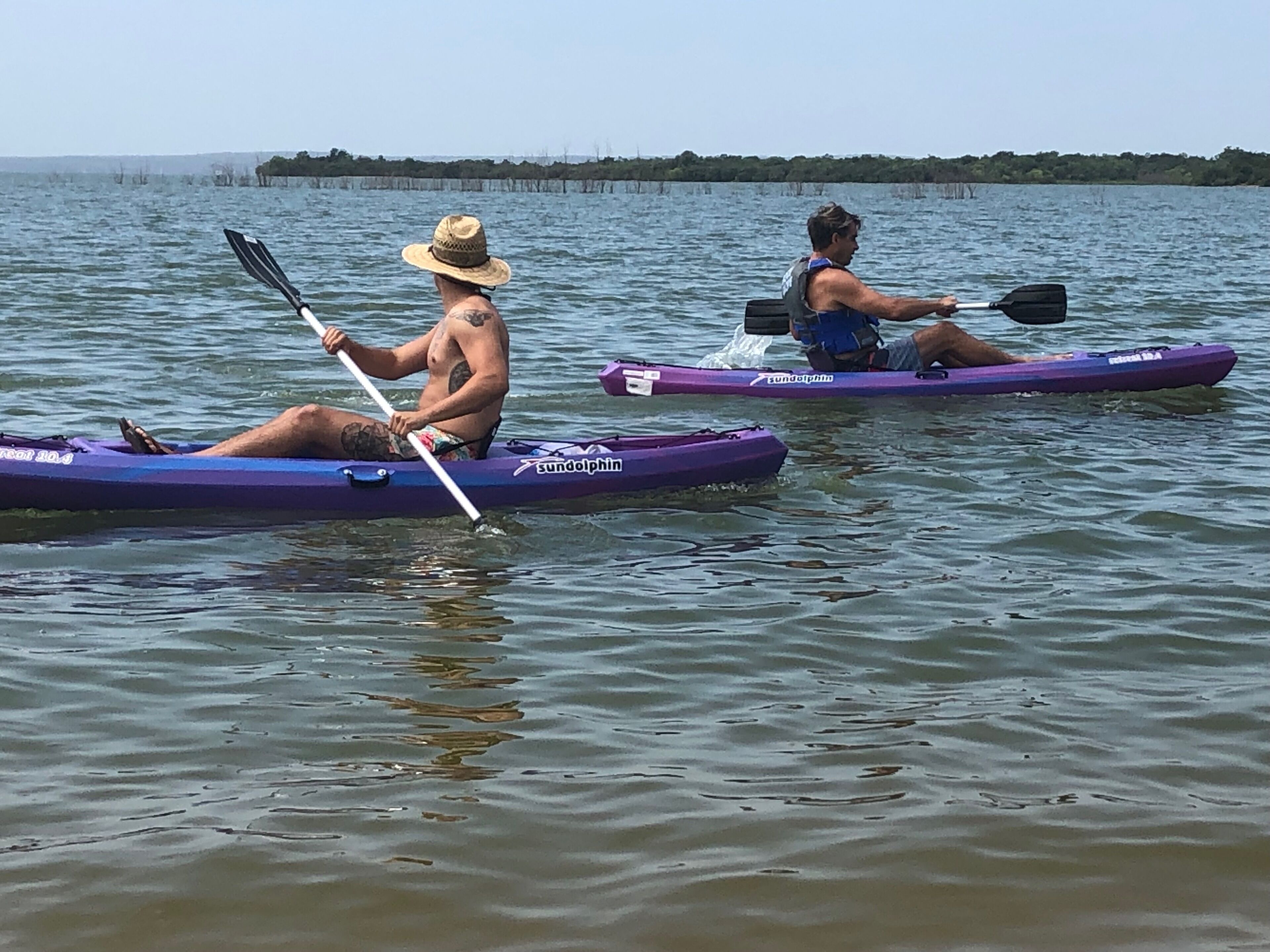 Two kayaks on calm water with a distant shoreline.