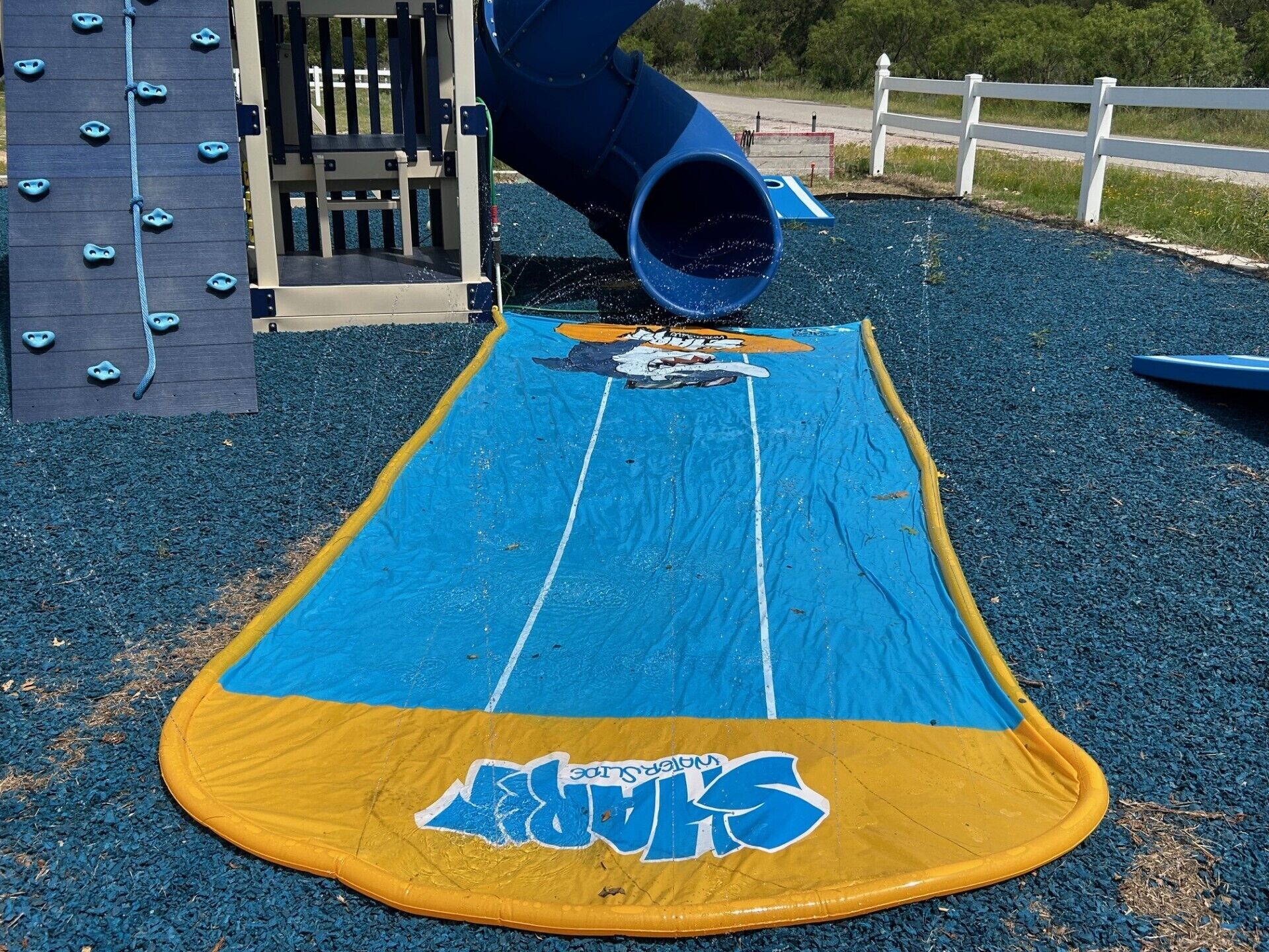 Une aire de jeux avec un toboggan bleu et un espace de jeux aux couleurs jaune et bleu.