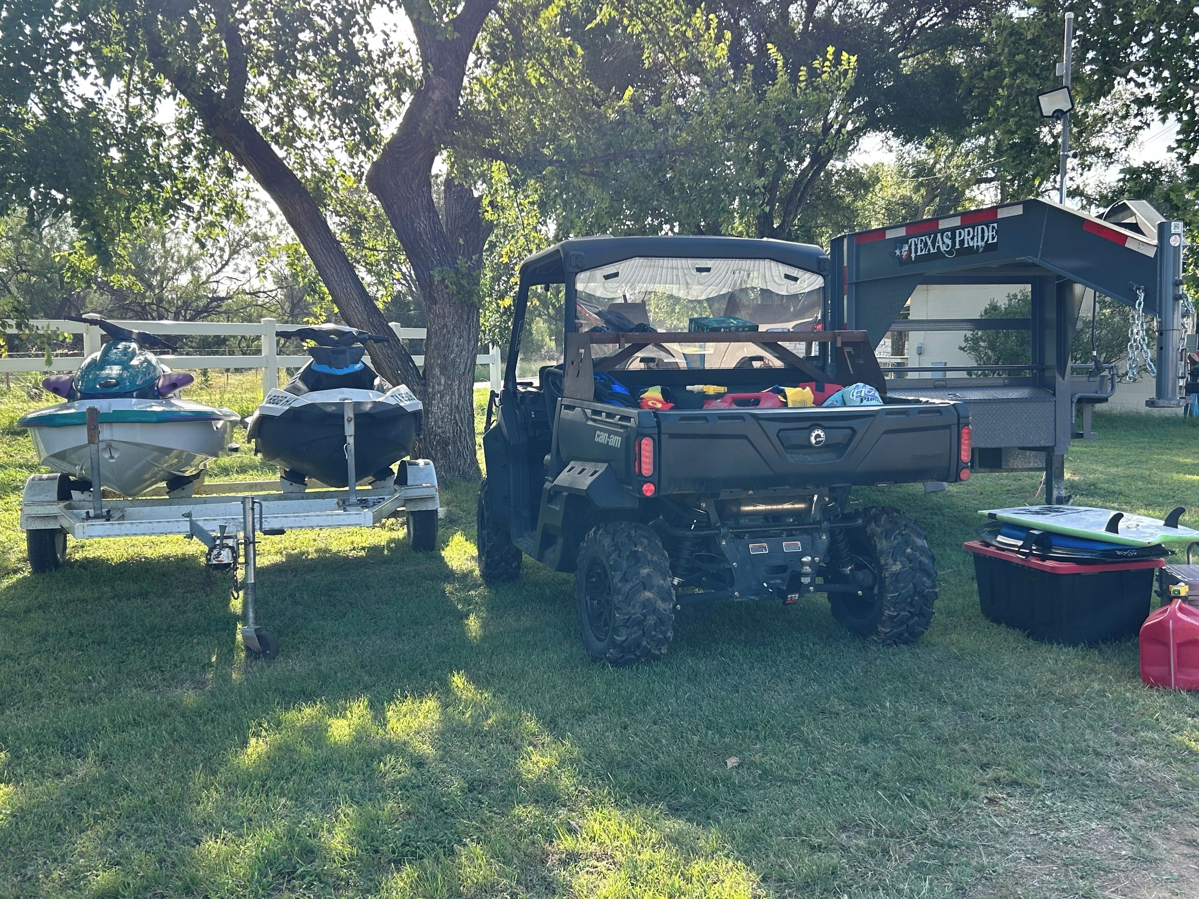 Ein Nutzfahrzeug mit einem Texas Pride Banner, ein Anhänger mit einem Boot und ein Quad.