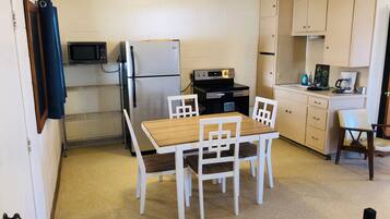 Une cuisine compacte équipée d’un réfrigérateur, d’une cuisinière, d’un four à micro-ondes et d’une table à manger avec des chaises.