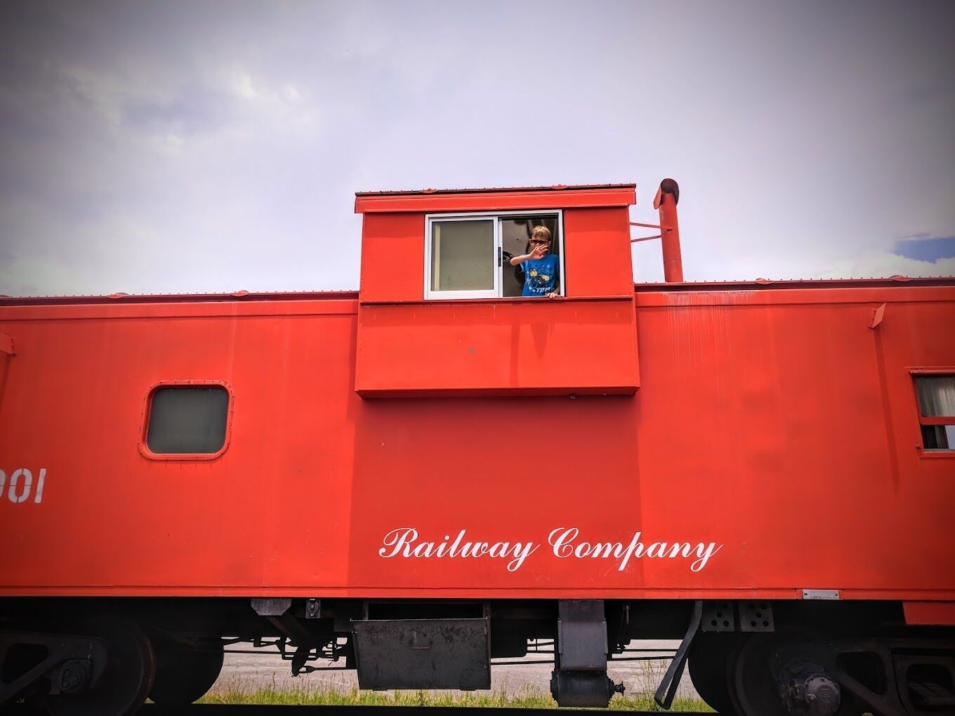 Un wagon de train rouge avec une petite fenêtre et une personne à l’intérieur.